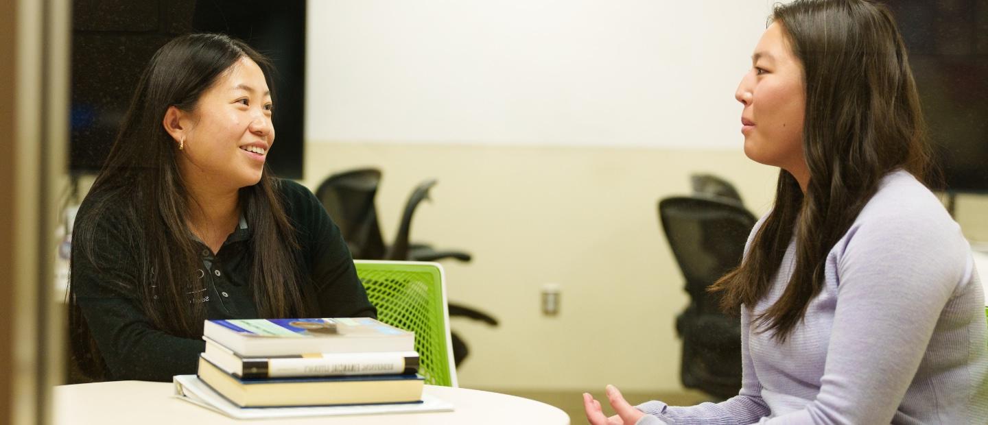 An adviser and student talking at a table.